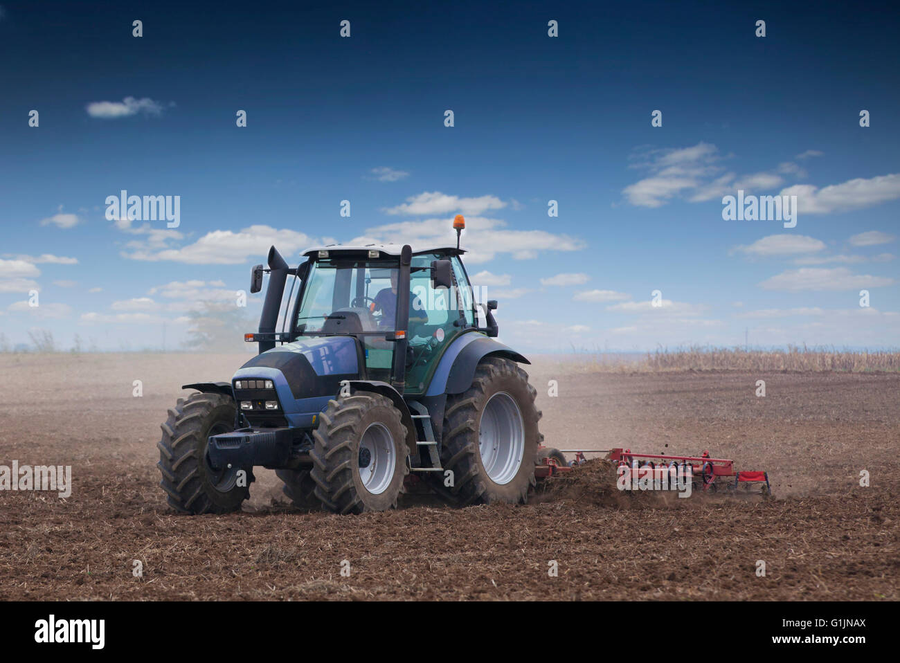 Young farmer in tractor preparing land for sowing Stock Photo