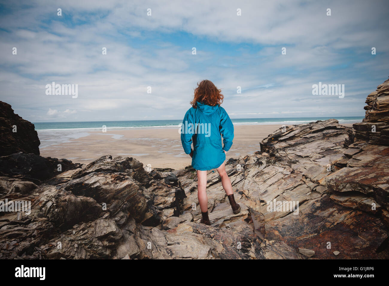 A young woman is standing on the coast and is looking at the sea Stock Photo