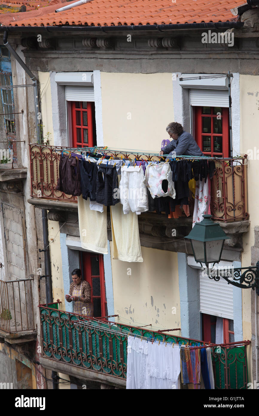 Portugal, city of Porto, women hanging laundry for drying on house balcony, daily routine