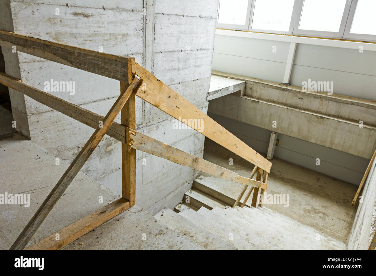 New concrete staircase with temporary wooden handrail, under