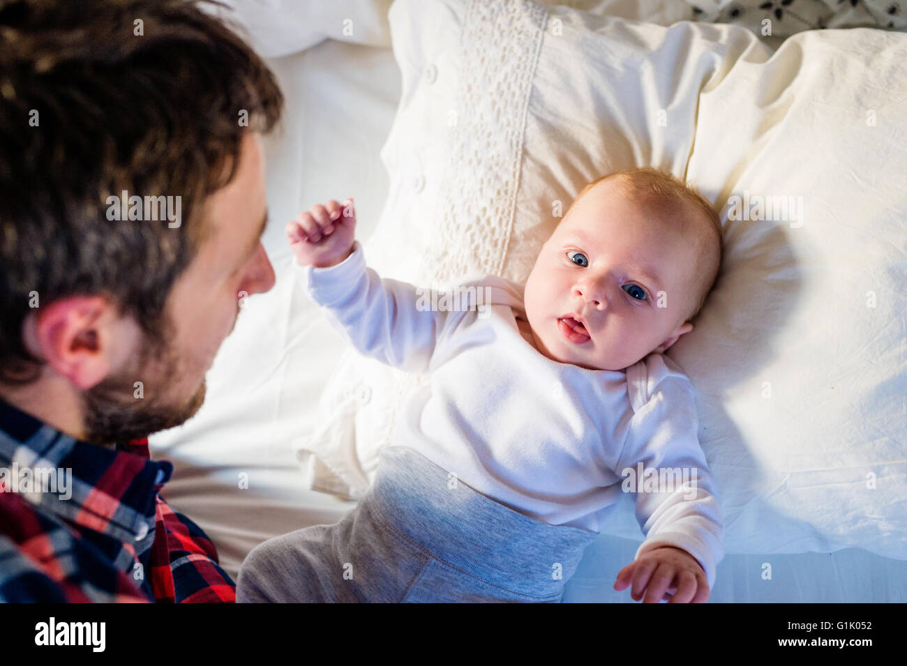 Baby boy lying on bed, with his father Stock Photo - Alamy