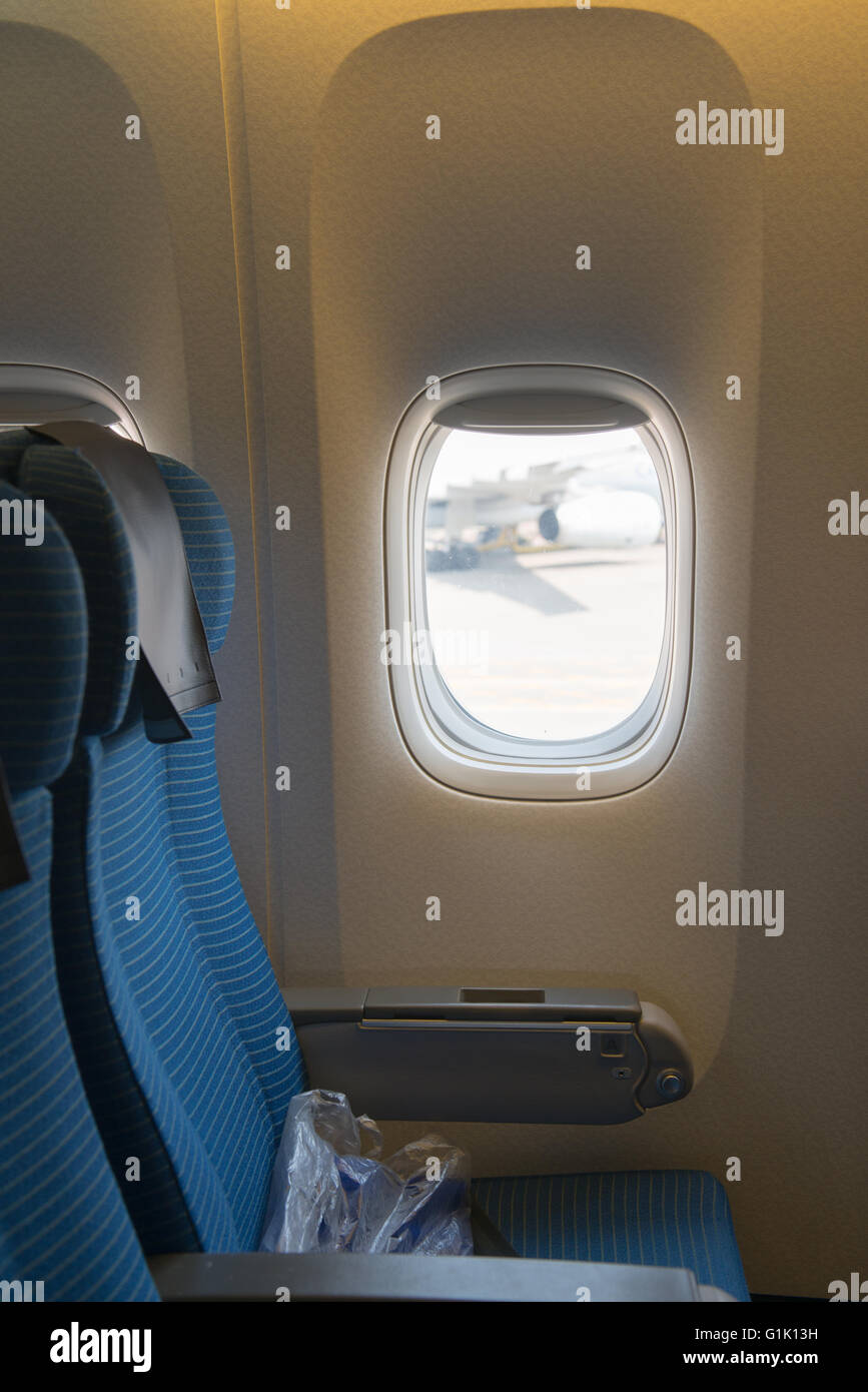 Blue passenger seat on a commercial airplane by window Stock Photo