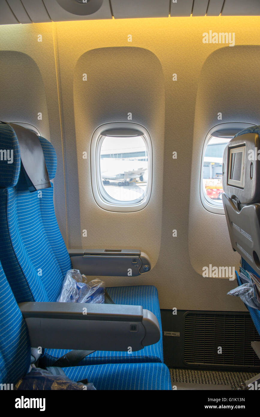 Blue passenger seat on a commercial airplane by window Stock Photo