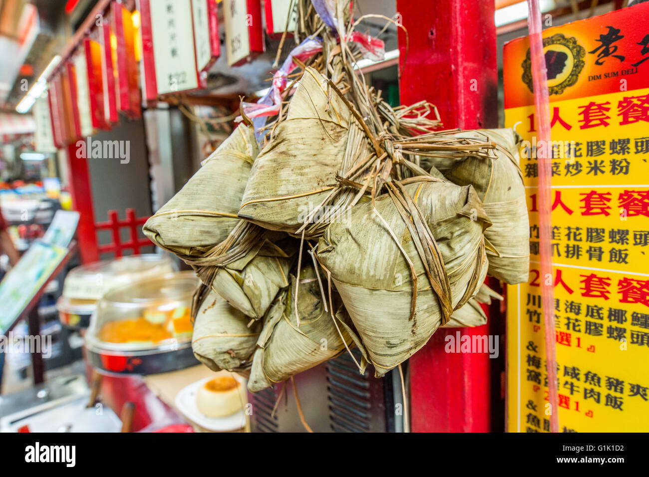 green leaf wrapped rice parcels hanging from string on side of building in China Stock Photo