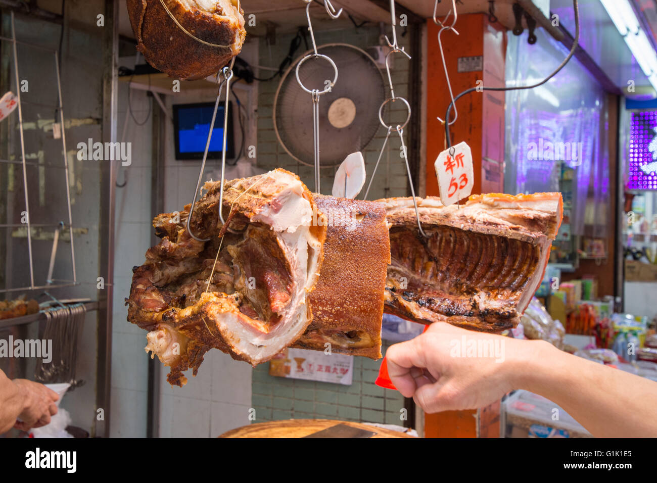 suckling pig roast on metal hooks at market Stock Photo