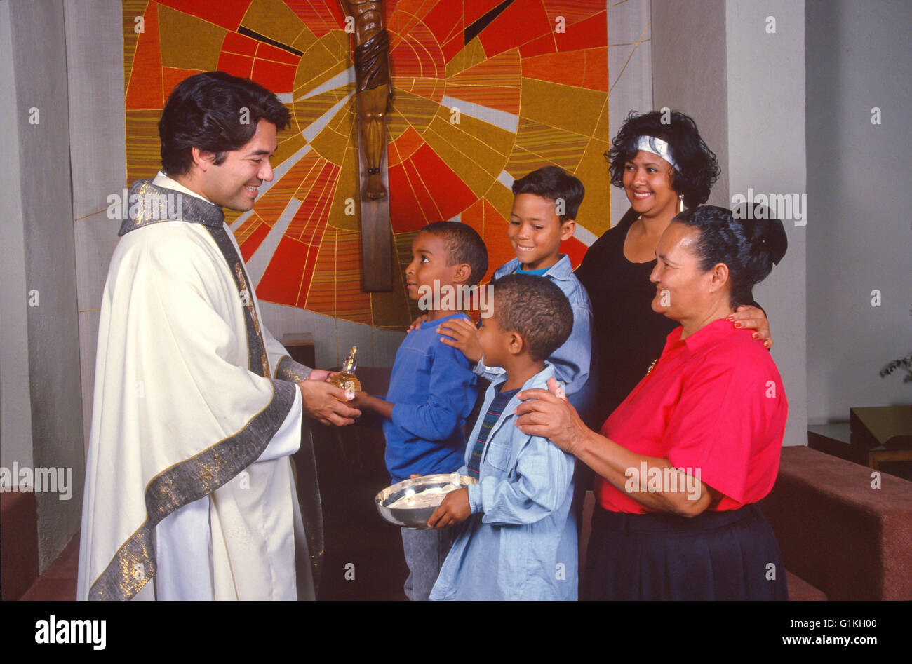 interracial Hispanic family of 5 presents gift Eucharist to Hispanic priest at Mass Liturgy wearing cassock MR  © Myrleen Pearson ..... Ferguson Cate Stock Photo