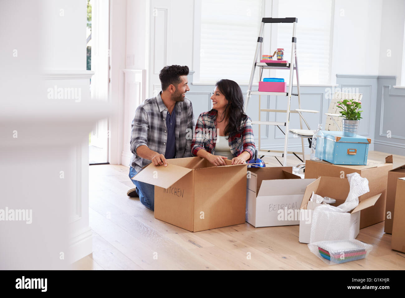 Hispanic Couple Moving Into New Home And Unpacking Boxes Stock Photo ...