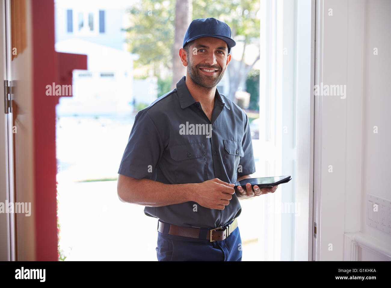 Courier Standing At Front Door With Digital Tablet Stock Photo
