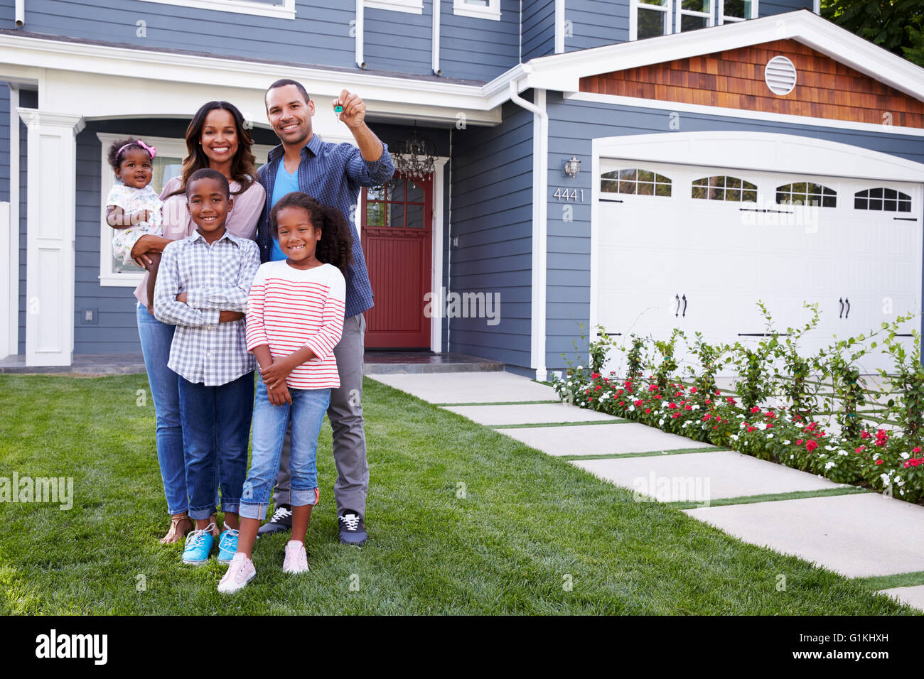 Happy black family standing outside their house, dad holding the key ...