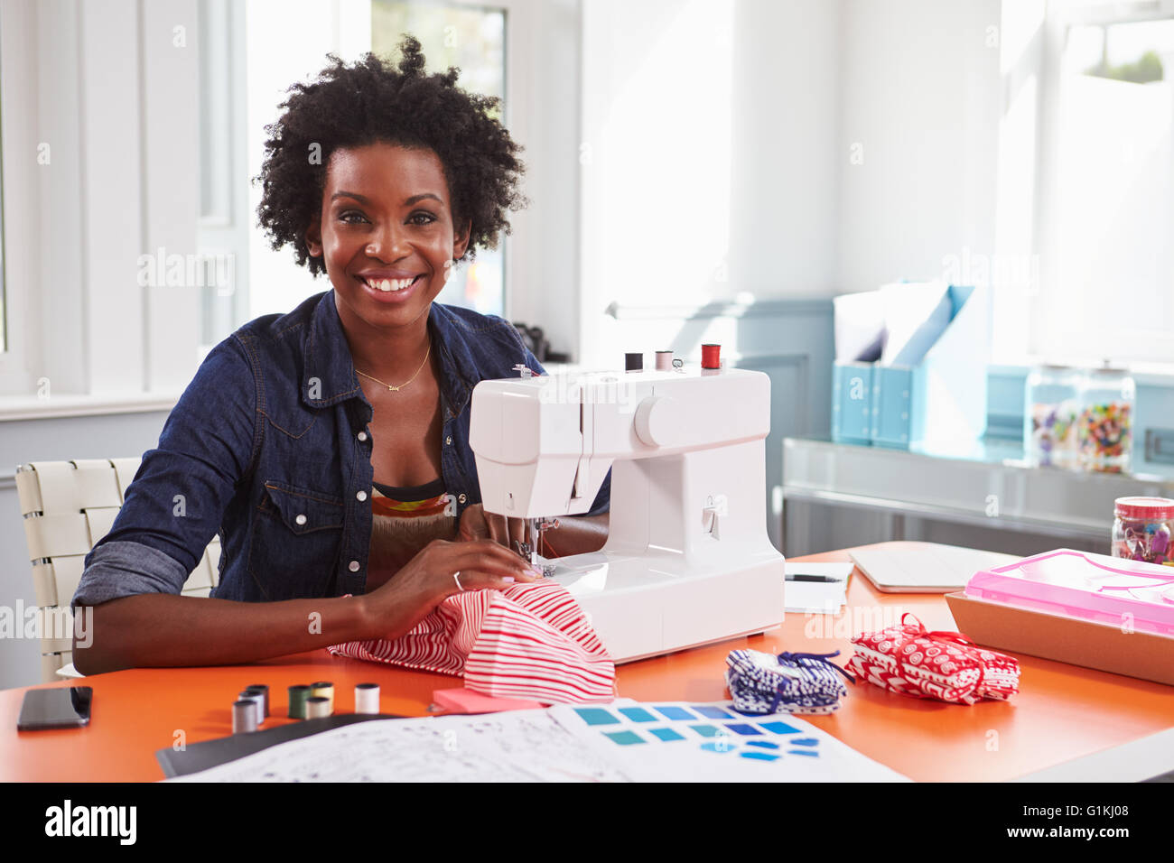 Young black woman using a sewing machine looking to camera Stock Photo