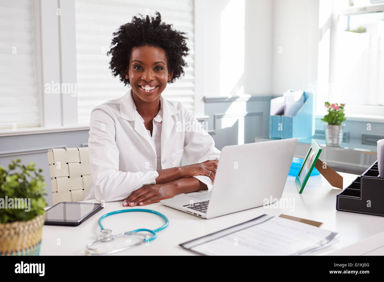 Female doctor in white coat looking to camera in an office Stock Photo