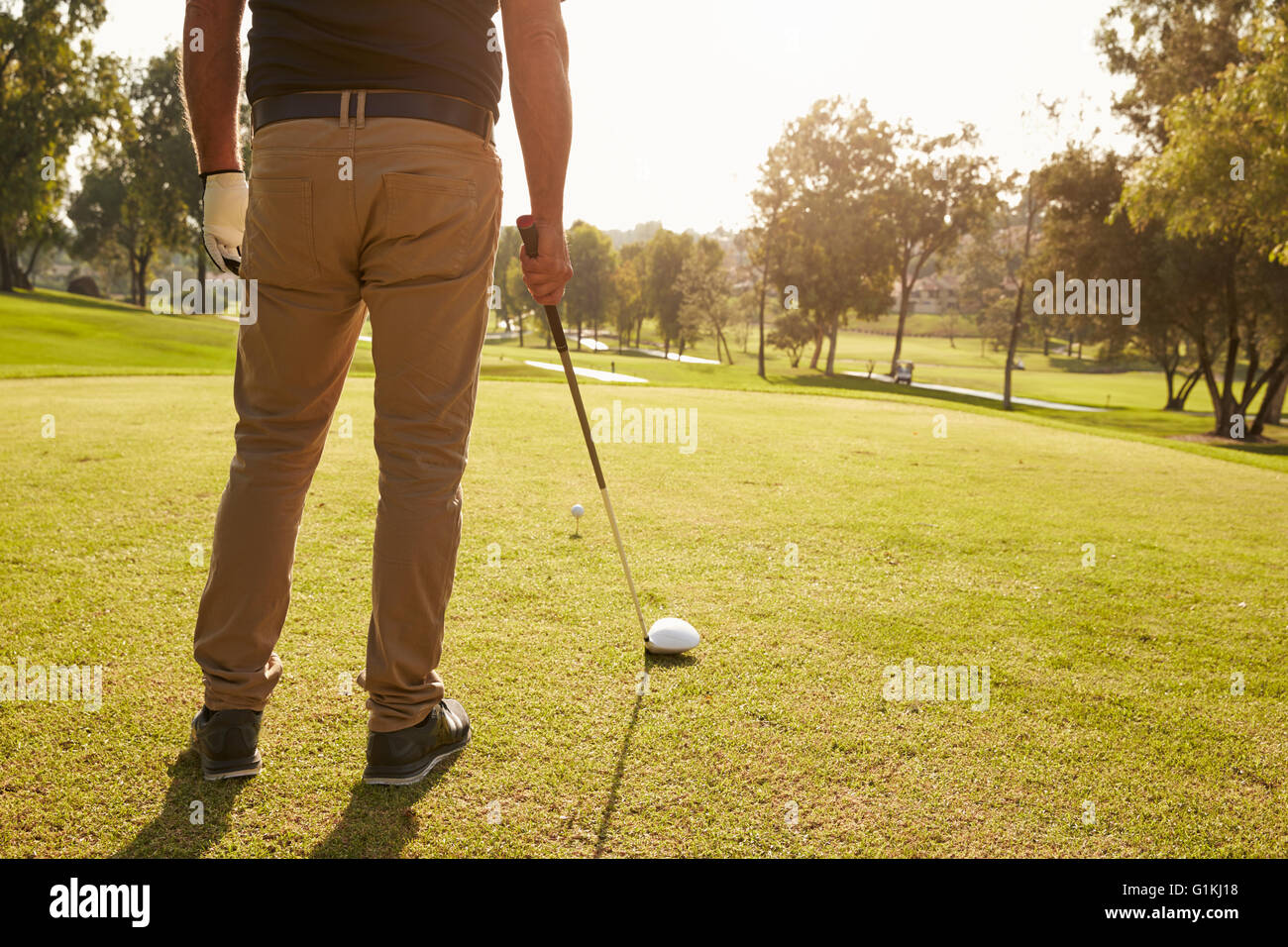 Close Up Of Male Golfer Lining Up Tee Shot On Golf Course Stock Photo