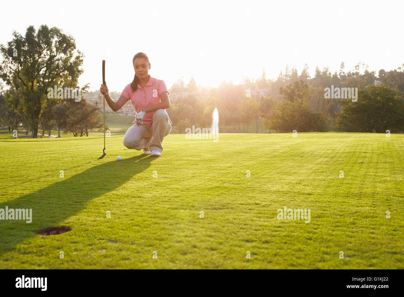 Female Golfer Lining Up Putt On Green Stock Photo