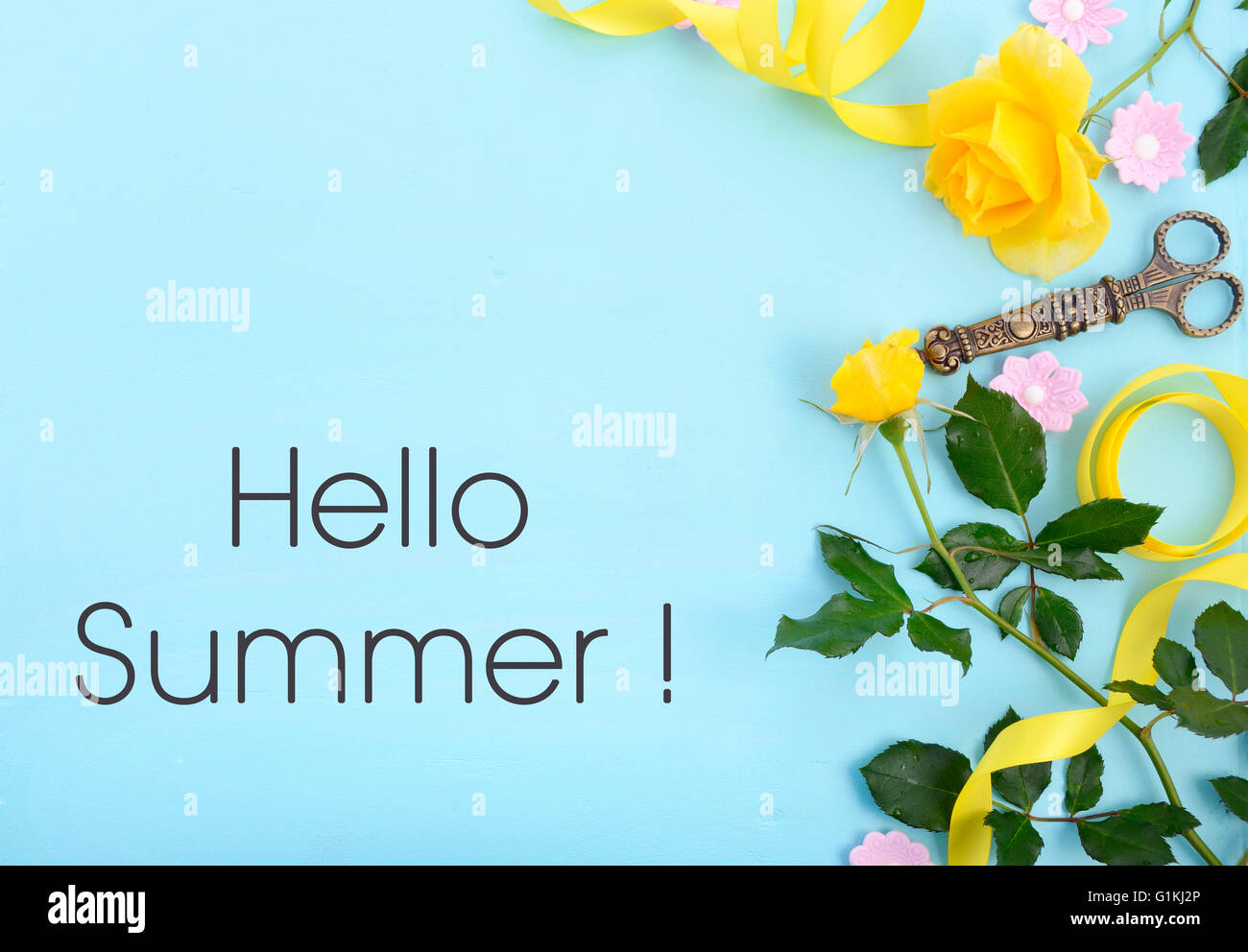 Summertime background with decorated borders of yellow roses, pink candy and yellow ribbon on pale blue wood table, with copy sp Stock Photo