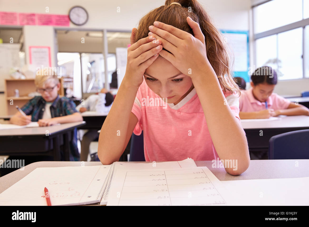 Schoolgirl with head in hands in an elementary school class Stock Photo