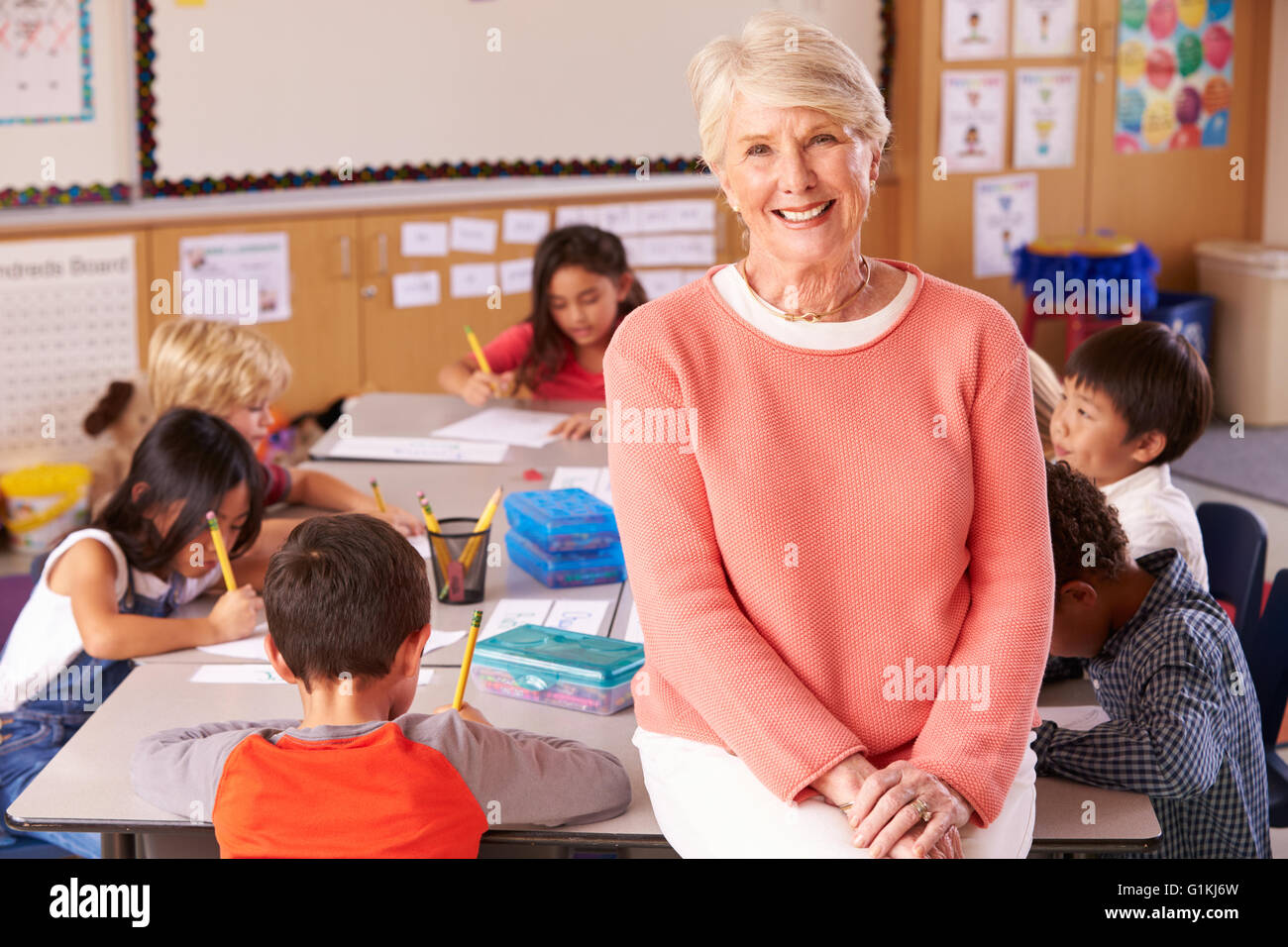 Senior teacher in classroom with elementary school kids Stock Photo
