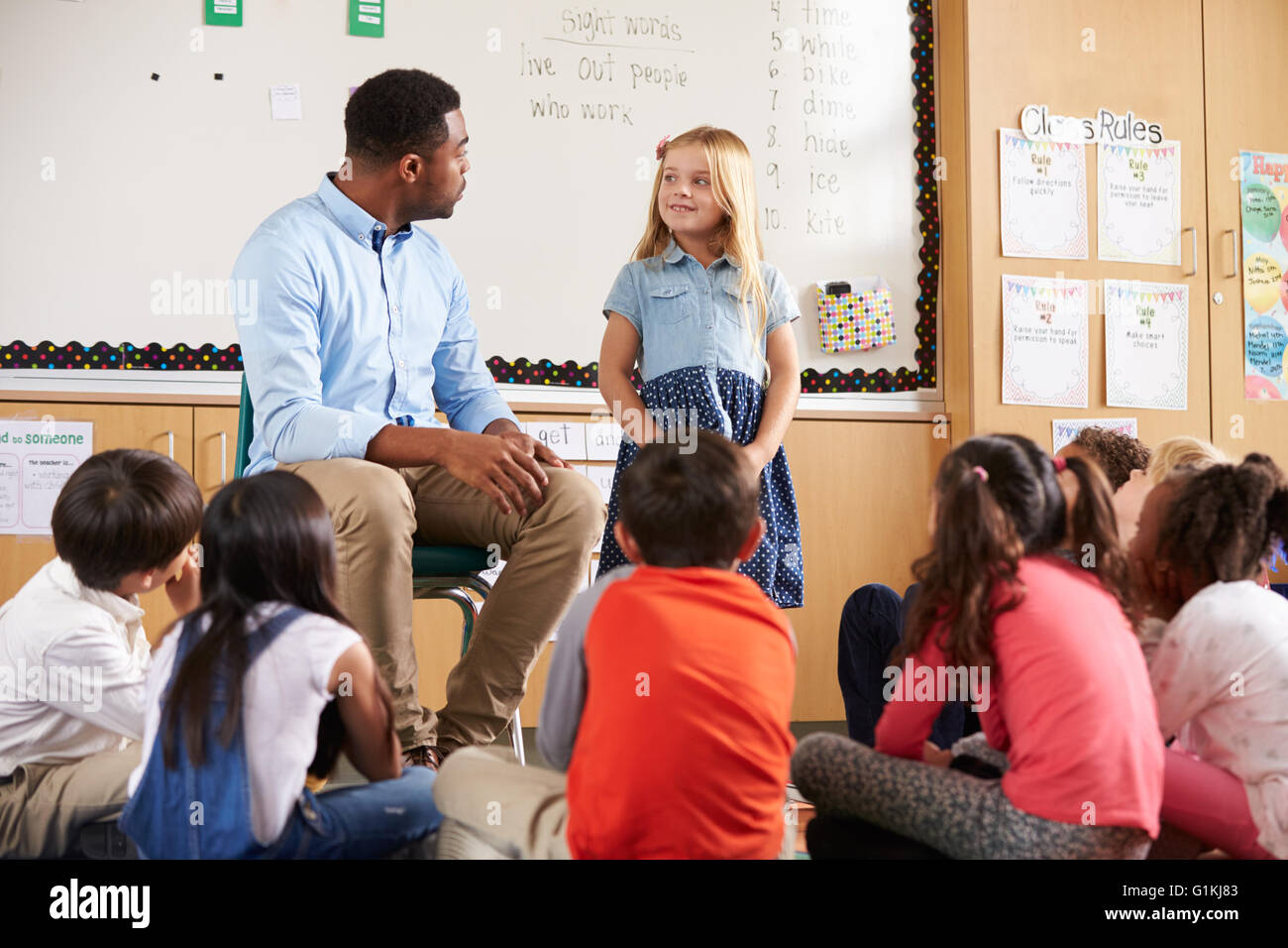 Schoolgirl at front of elementary class with teacher Stock Photo