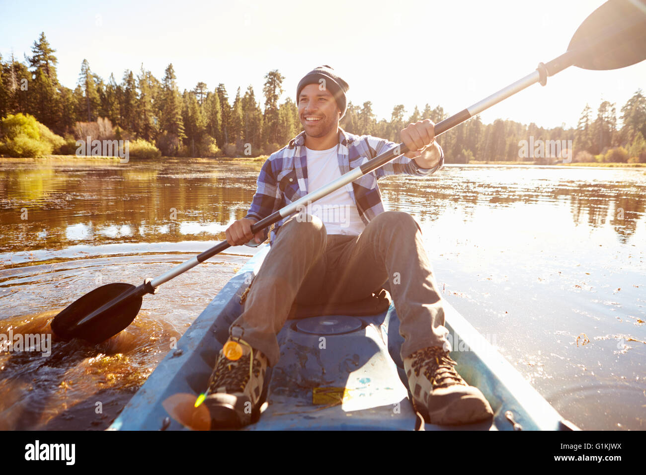 Young Man Rowing Kayak On Lake Stock Photo
