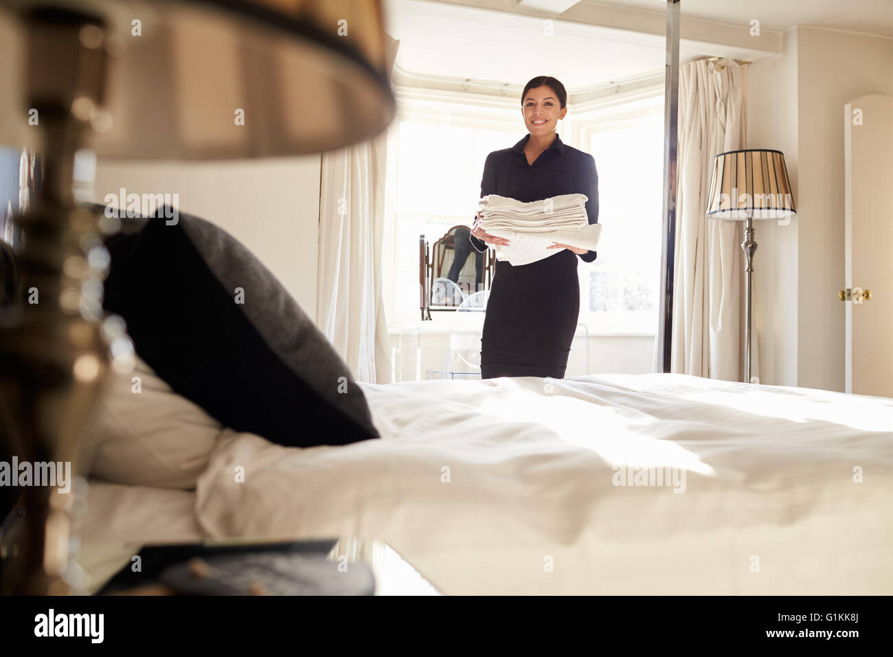 Chambermaid carrying linen in hotel bedroom, low angle view Stock Photo