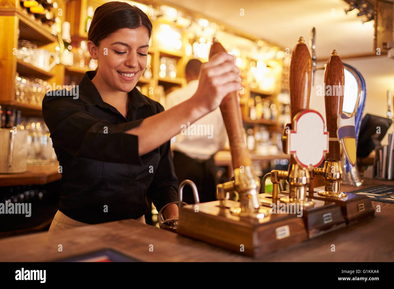 A young woman working behind a bar preparing drinks Stock Photo - Alamy