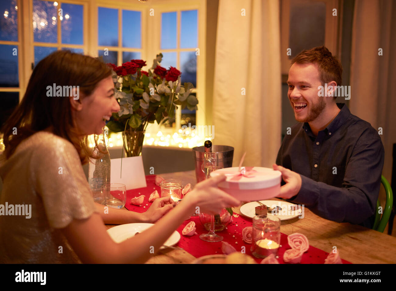Man Gives Woman Gift At Romantic Valentines Day Meal Stock Photo