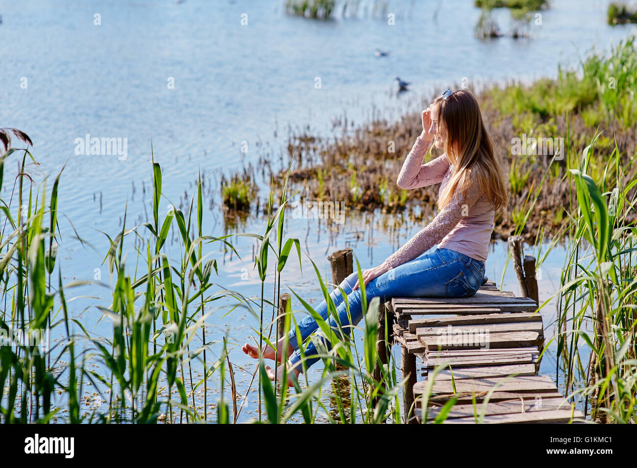 beautiful woman sitting on wooden pier the river Stock Photo