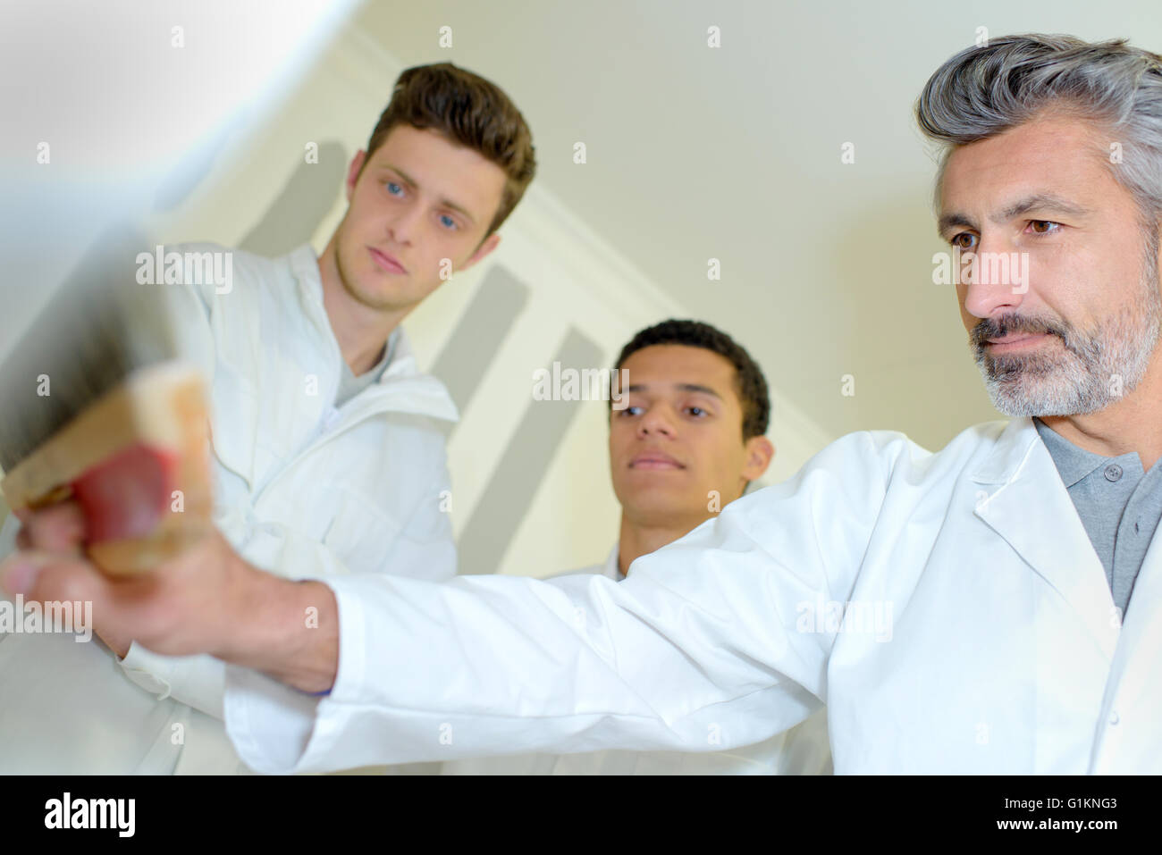 Two apprentices watching tutor with brush Stock Photo