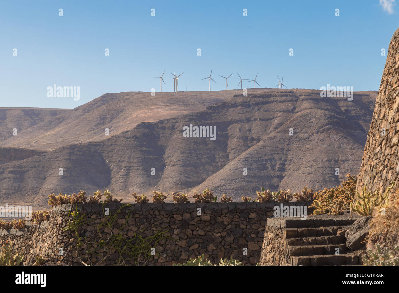 Wind turbines on a mountain top. Viewed from the Lanzarote Cactus Garden. Designed by César Manrique. Stock Photo