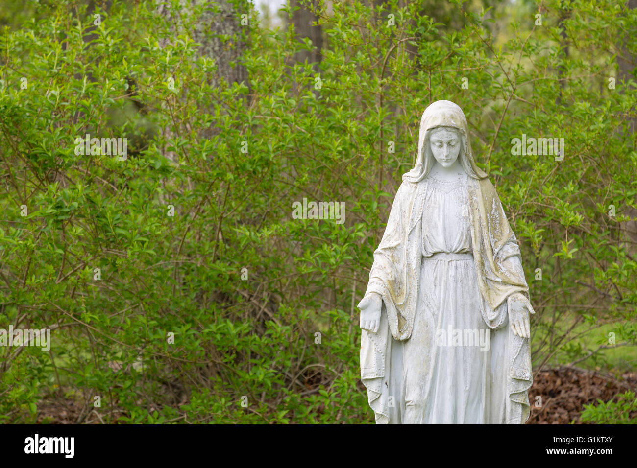 stone statue of Mary in prayer with open palms facing forward Stock