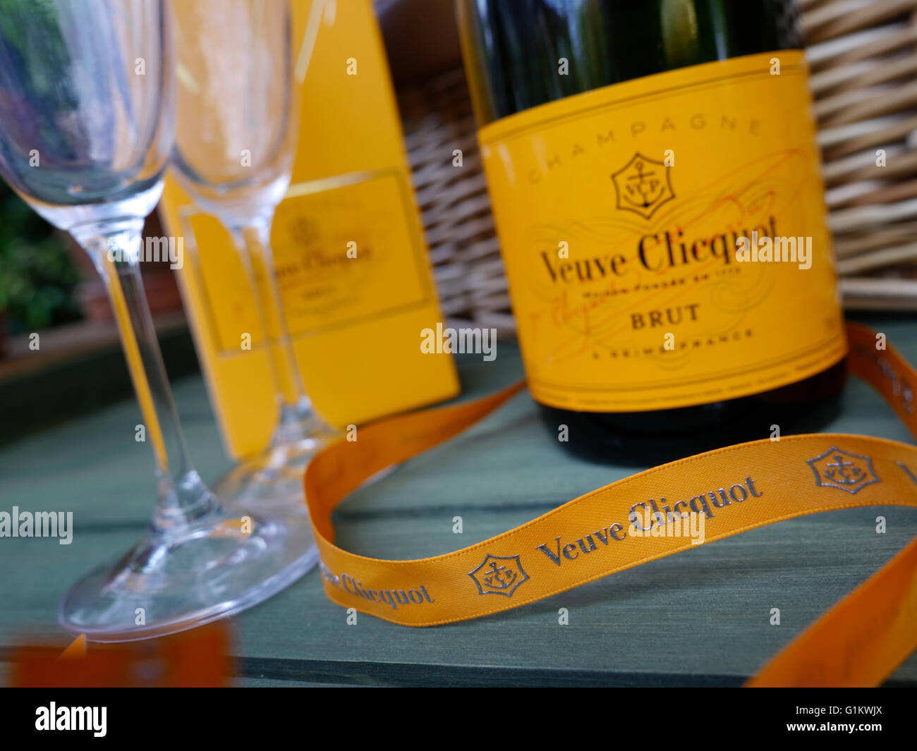 Veuve Clicquot Brut luxury Champagne and glasses on alfresco garden picnic table with picnic hamper basket behind Stock Photo