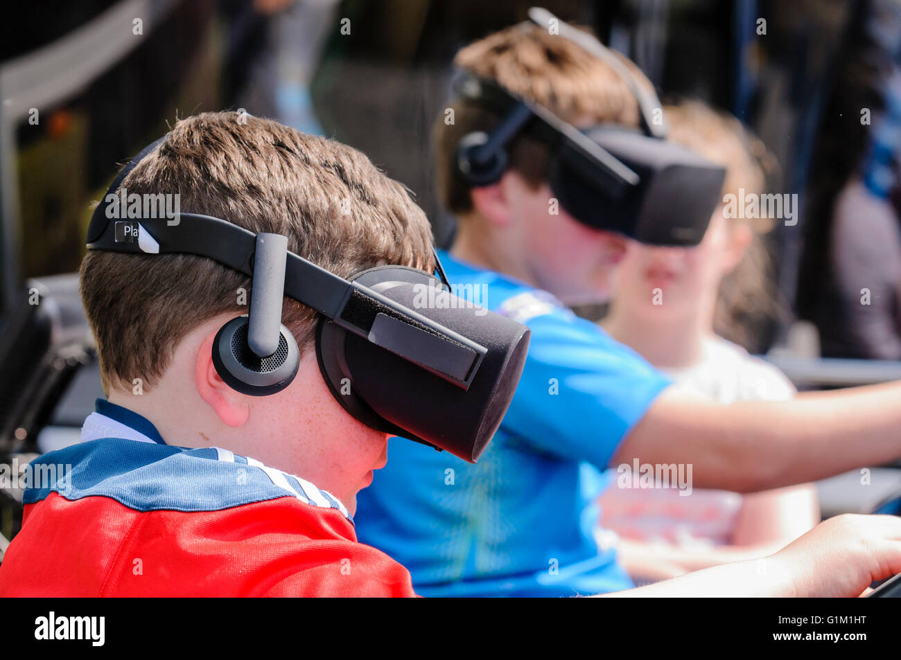 Two boys use Oculus Rifts on a tractor driving simulator - Stock Image