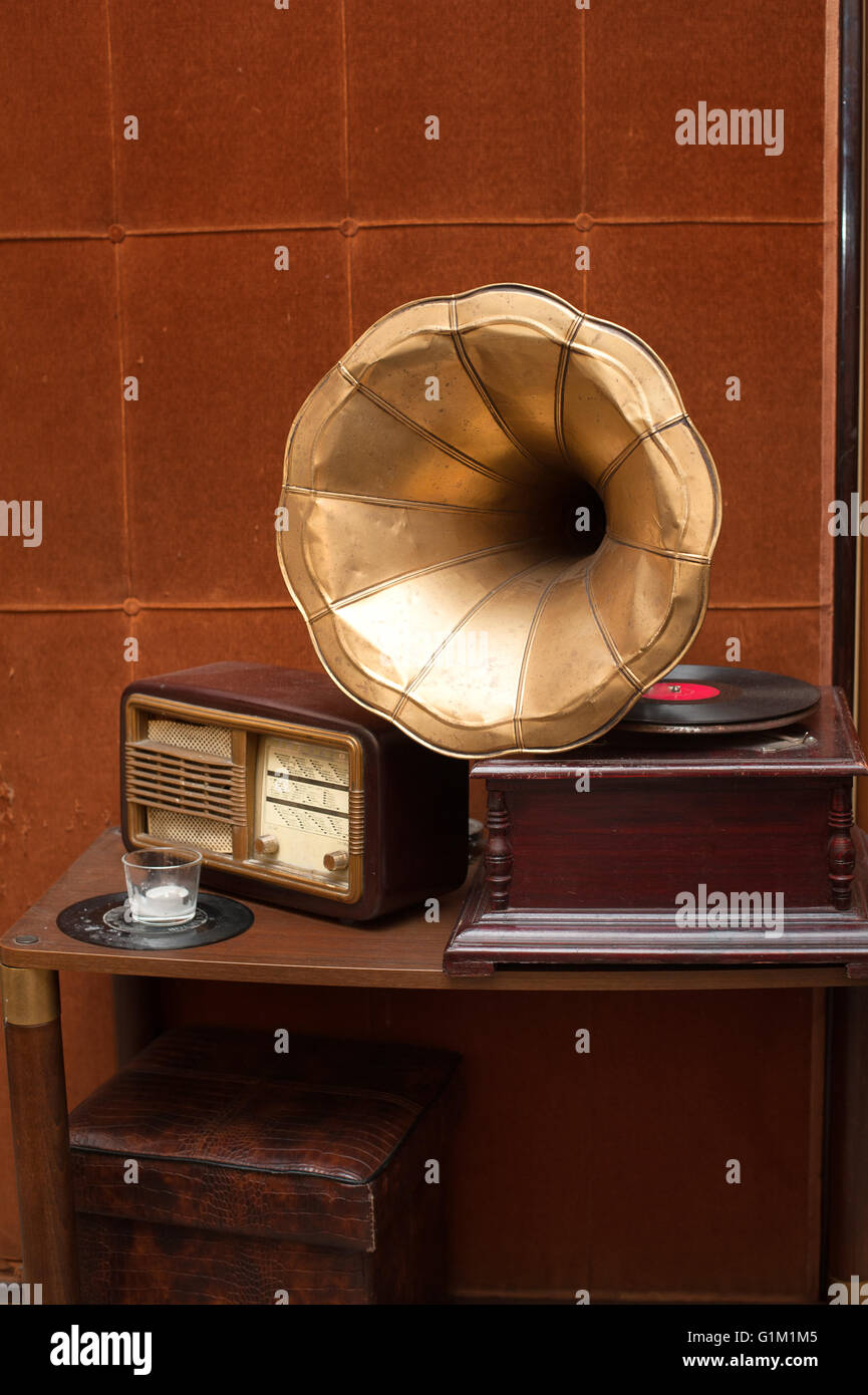 Antique gramophone with golden horn and radio on table on vintage brown wall background Stock Photo