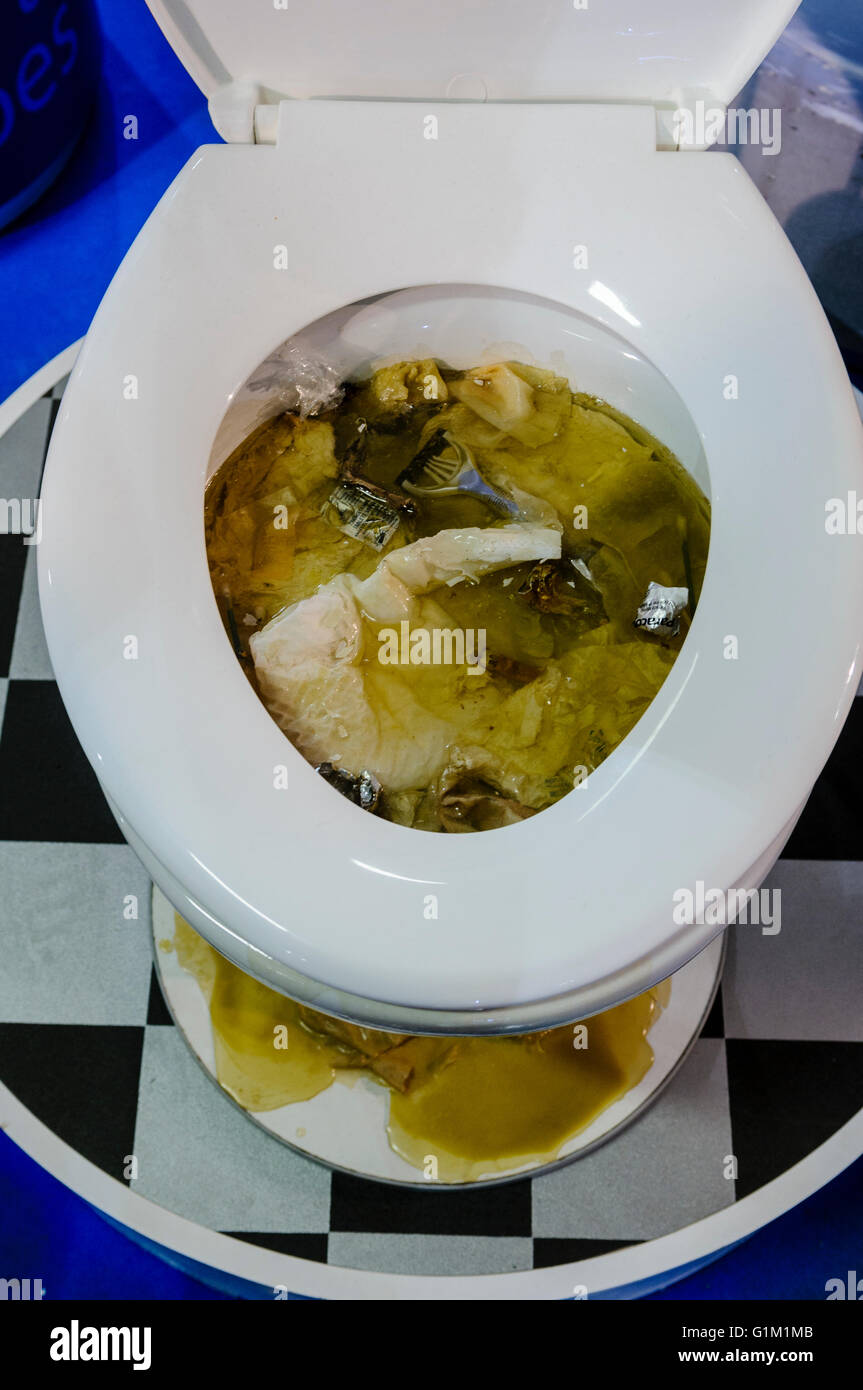 Toilet blocked with rubbish and toilet roll, overflowing onto the bathroom floor. Stock Photo