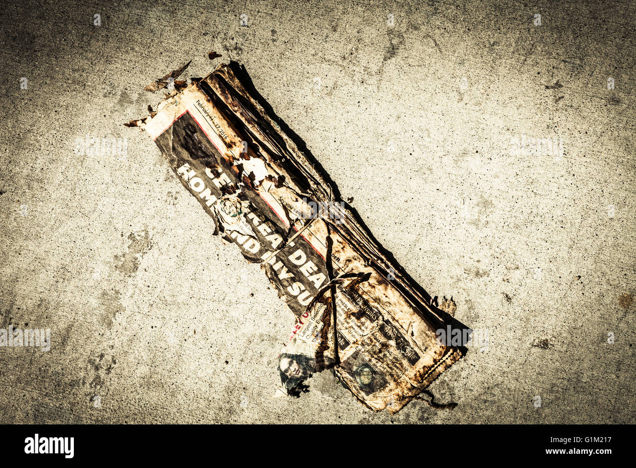 Tattered old newspaper on a cement driveway delivered but not picked up with vignette and coloration. Stock Photo