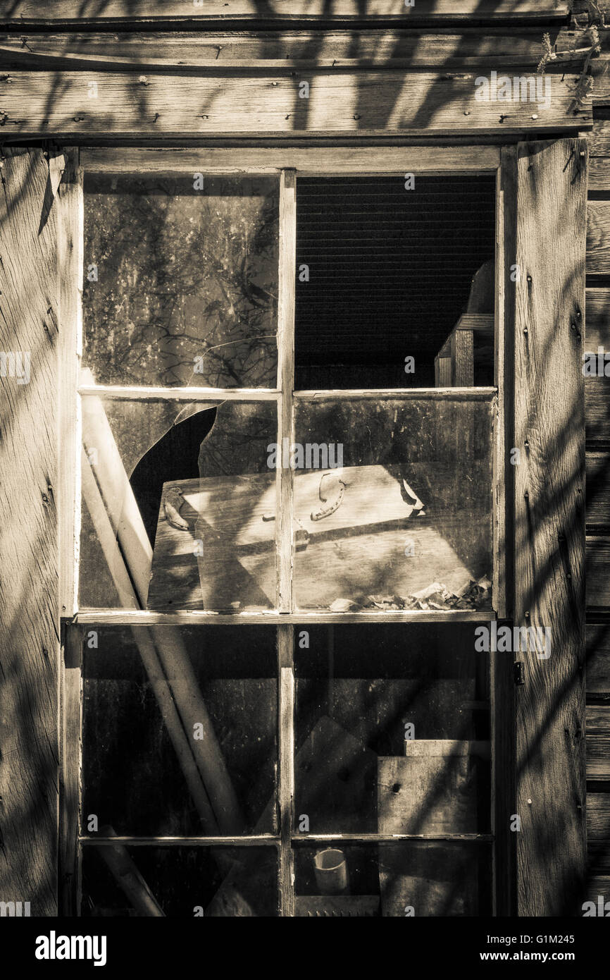 Rustic broken window in a western ghost town with strange shadows in black and white. Stock Photo