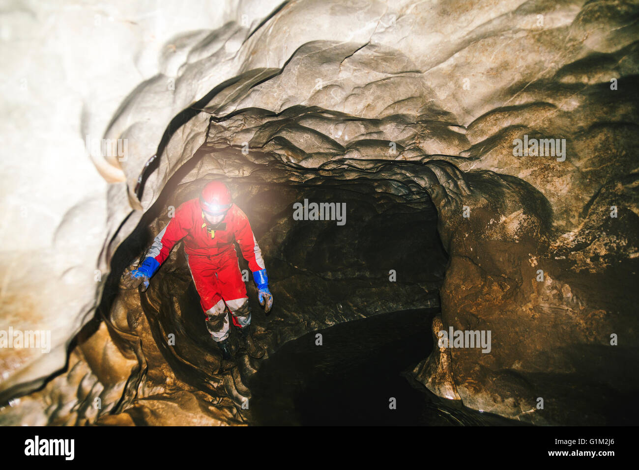 Caucasian hiker wearing headlamp in cave Stock Photo