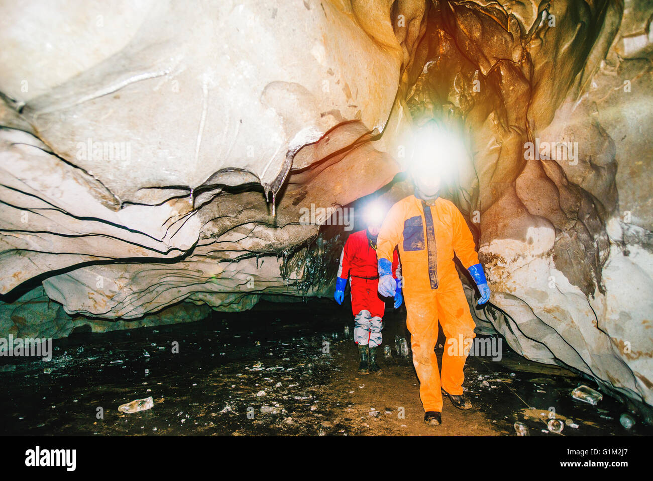 Caucasian hikers wearing headlamps in cave Stock Photo