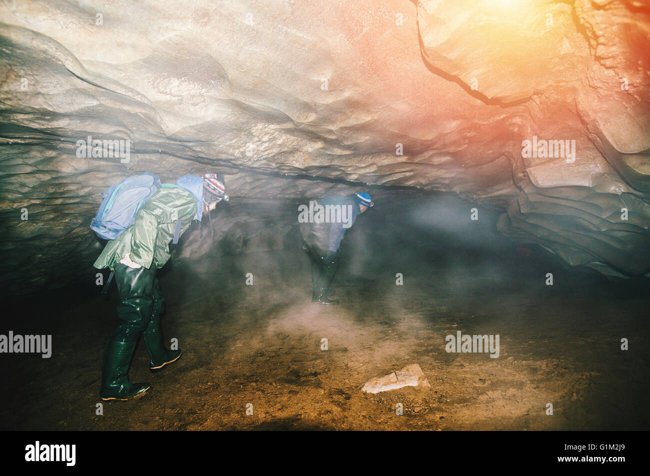 Caucasian hikers exploring cave Stock Photo