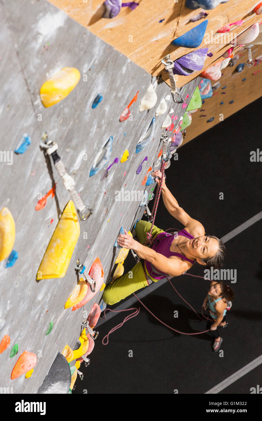 Woman belaying climber on rock wall Stock Photo