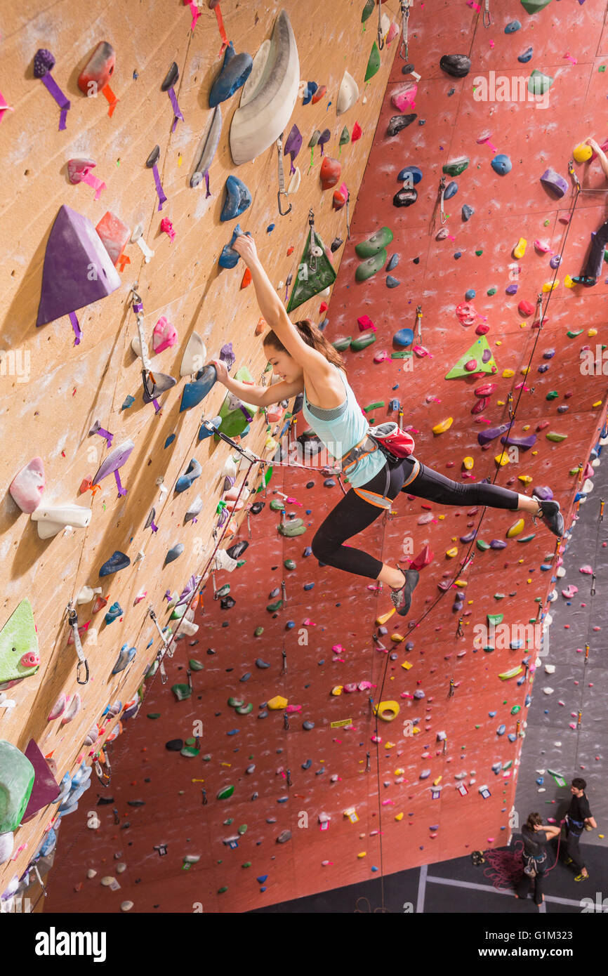 Caucasian woman climbing rock wall Stock Photo