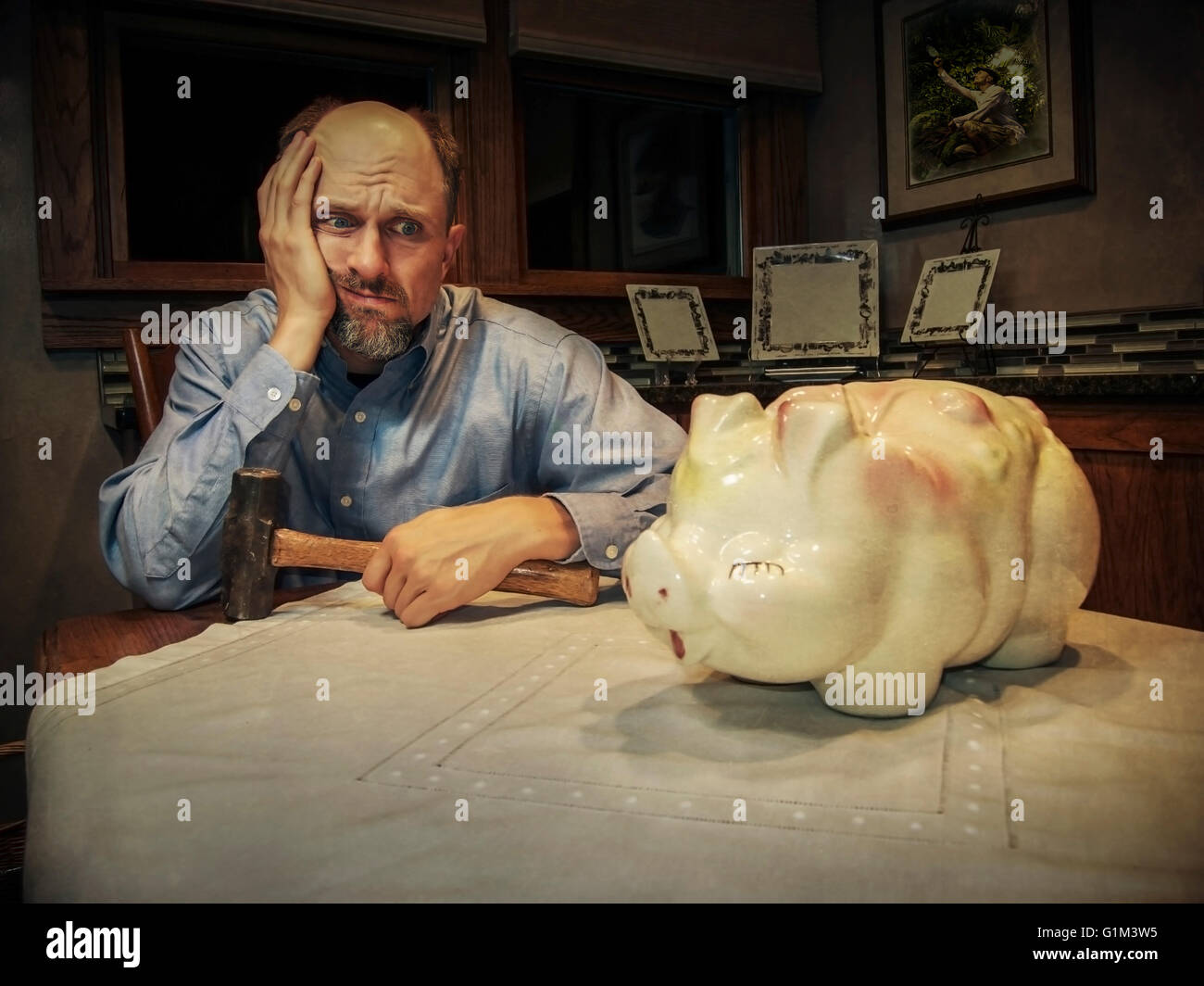 Caucasian man debating smashing piggy bank Stock Photo