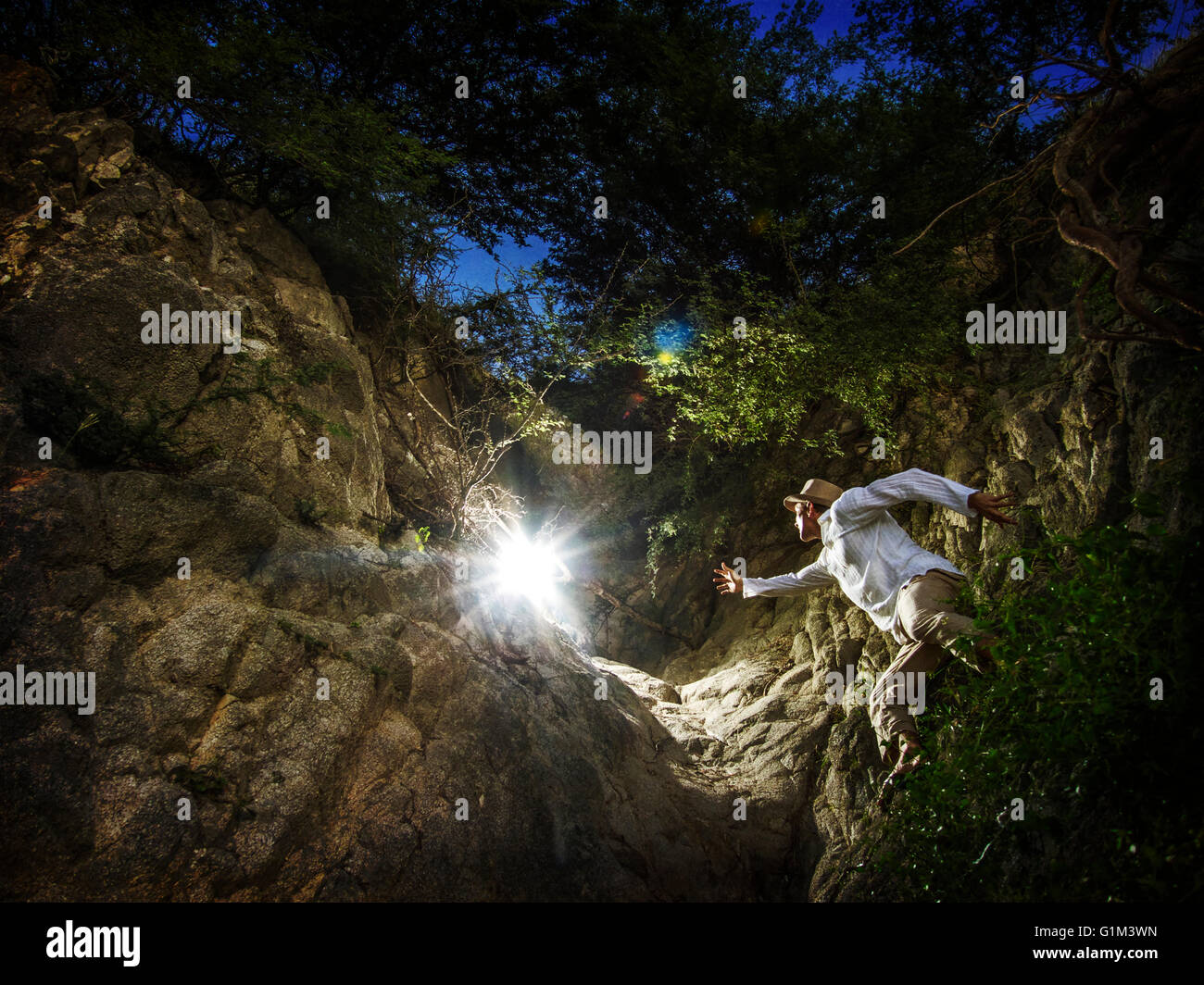 Caucasian man reaching for light in forest Stock Photo