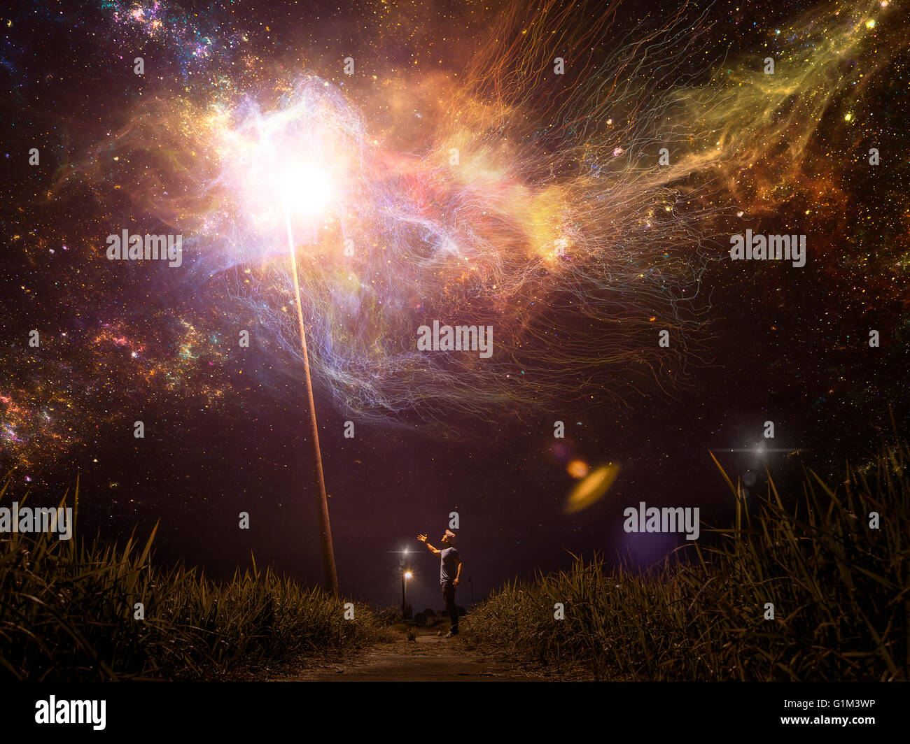 Caucasian man reaching towards light in starry night sky Stock Photo