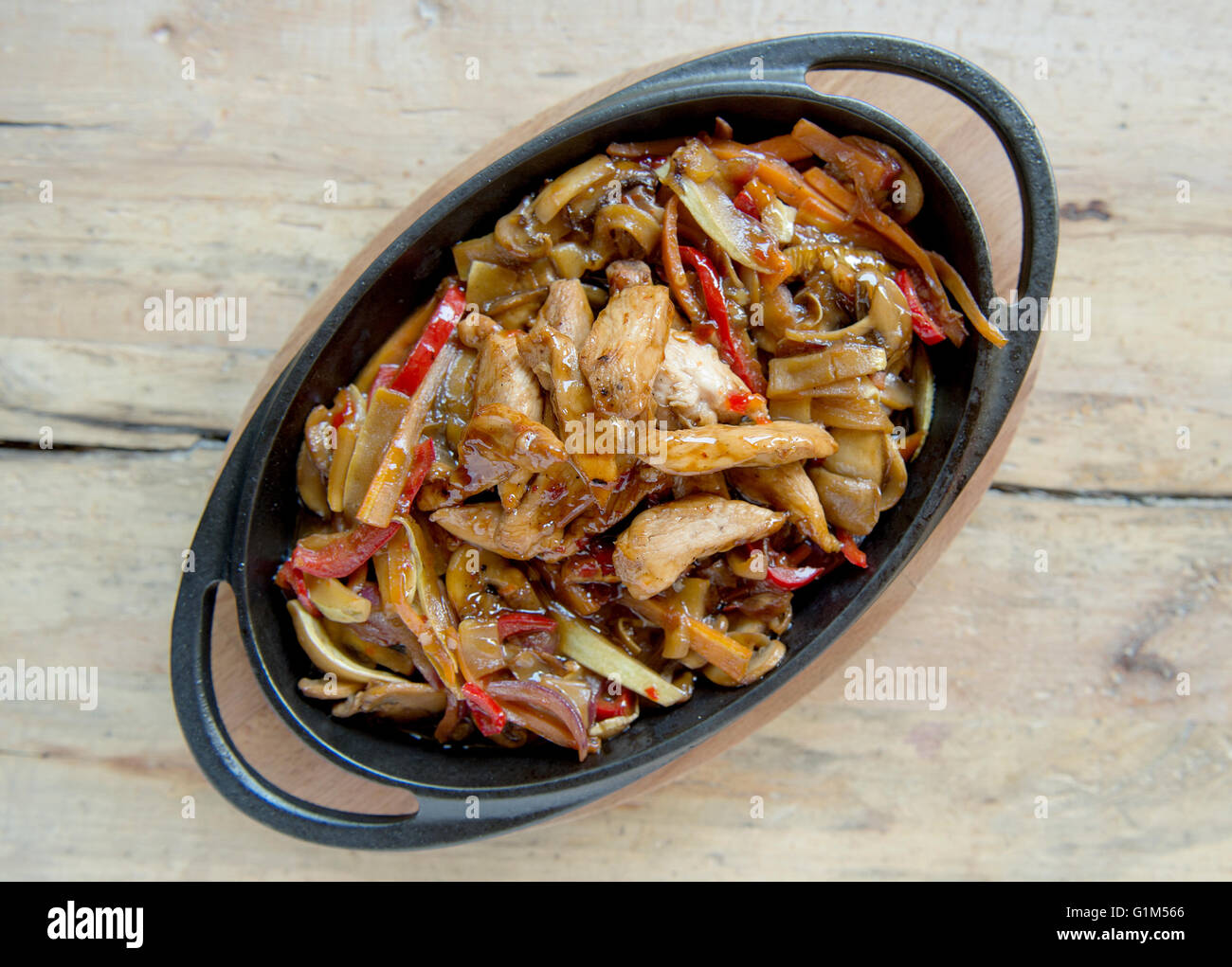 delicious spicy chicken pan on wooden table Stock Photo