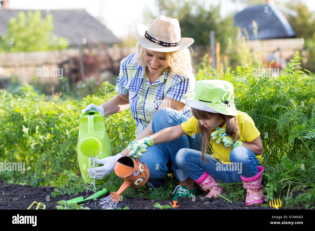 Mother and toddler daughter gardening and watering Stock Photo
