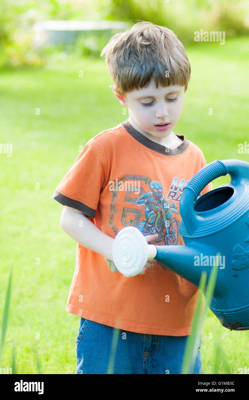boy watering the garden with watering can Stock Photo Alamy
