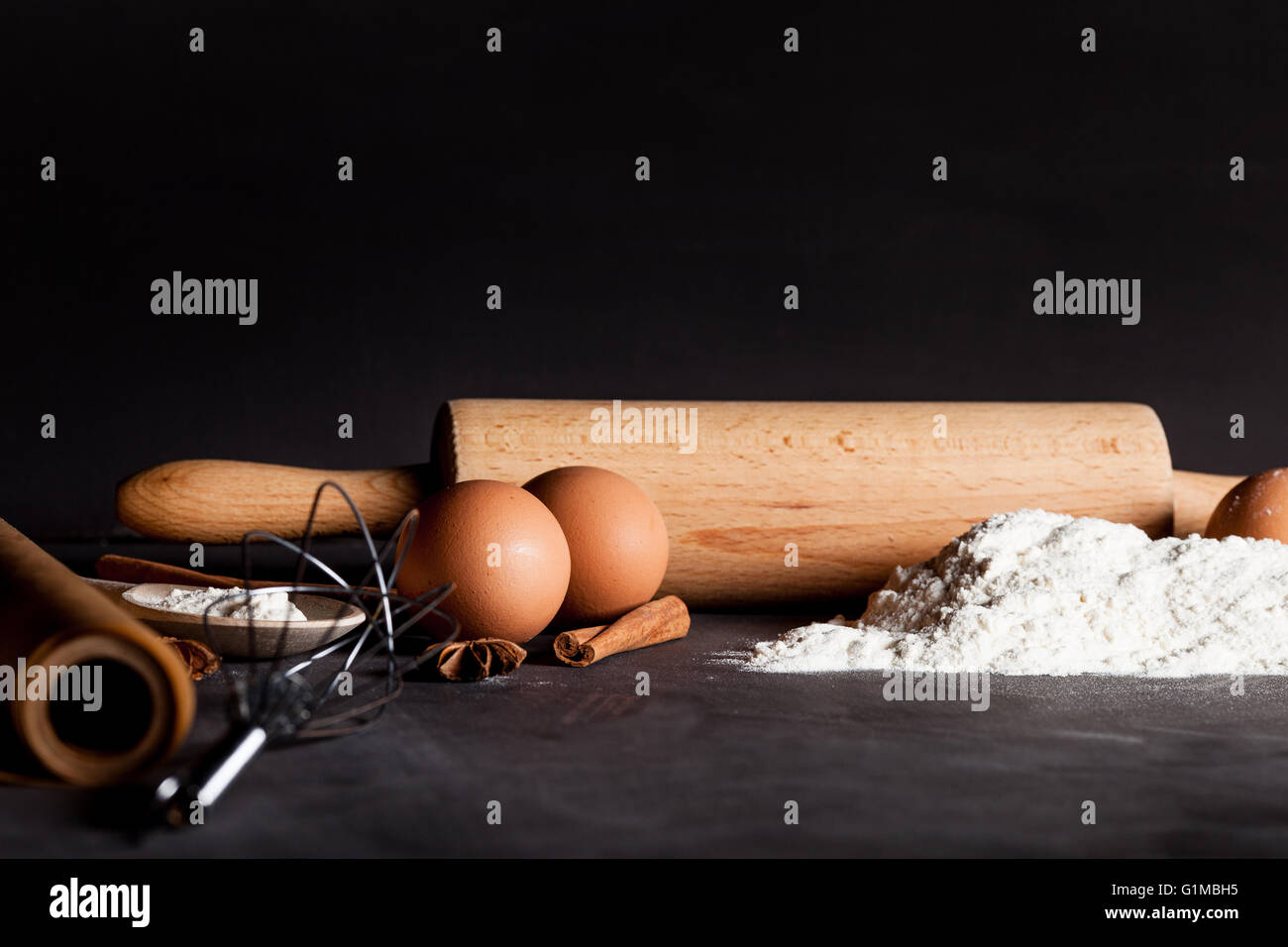 Ingredients like eggs, flour, cinnamon, anise, rolling pin, paper on blackboard Stock Photo