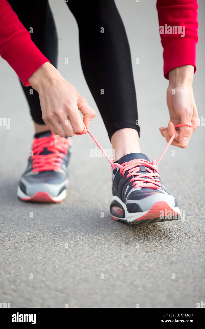 View of Sporty woman tying shoelace on sneakers before training. Female athlete ...