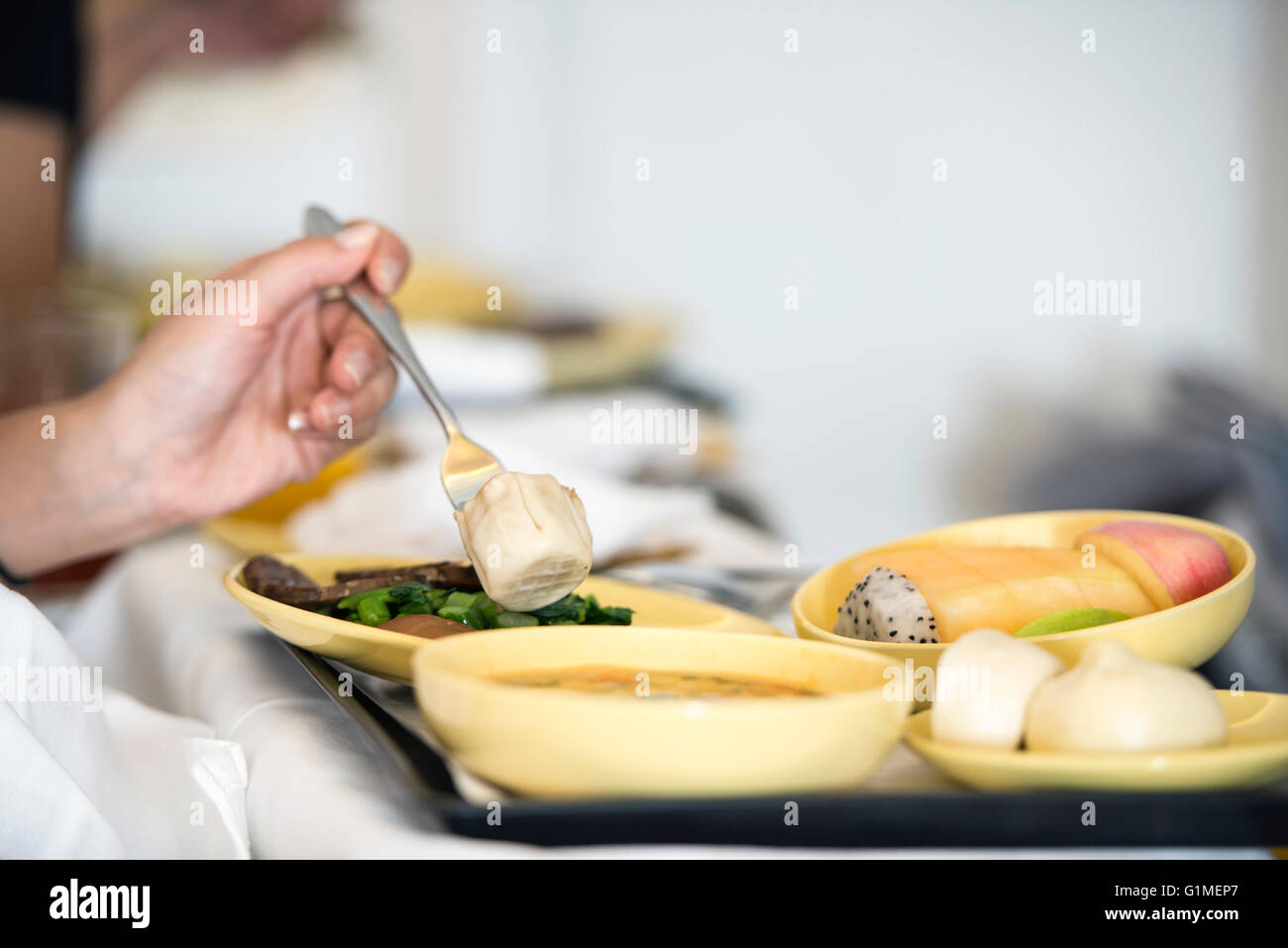 left-handed woman eating airline meal Stock Photo