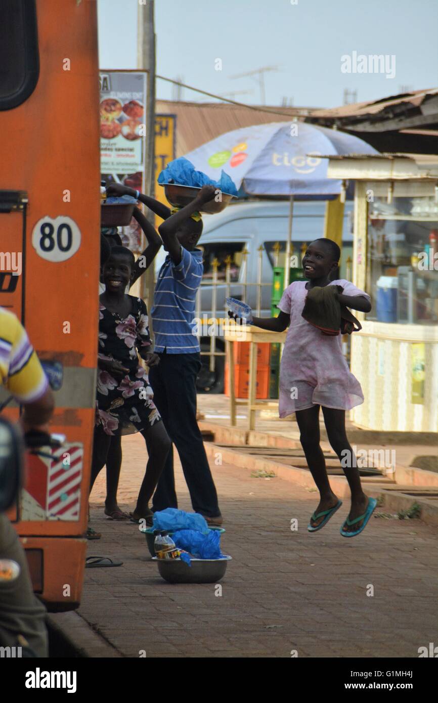 A small girl is exited, to have made a sale of one 500 ml - bag of filtered water. This street sales can be seen all over Ghana. Stock Photo